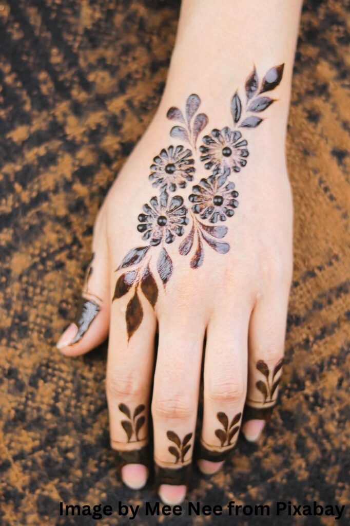Artful mehndi design creation on a woman palm.