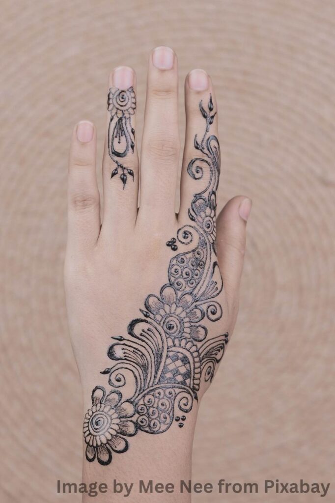 Black mehandi design tattoo on the wrist of a woman.