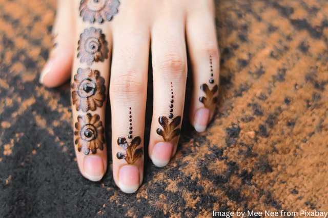 मेहंदी डिजाइन फोटो of a cute girl with small flower design of mehndi on her hand.