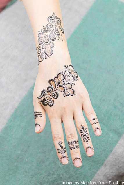 A woman hand adorned with a flower pattern in a simple mehndi design featuring henna tattoos. सिंपल मेहंदी डिजाइन