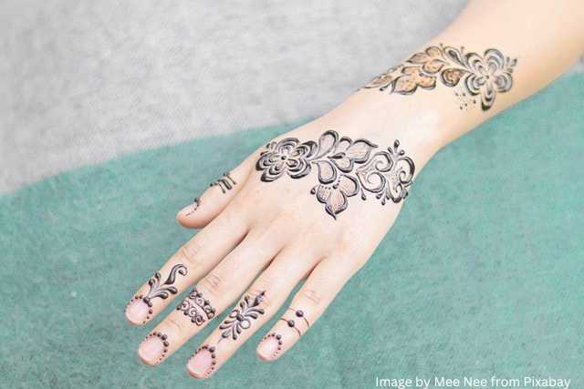 एक महिला के हाथ साधारण, सिंपल मेहंदी डिजाइन मेहंदी डिज़ाइन से सजे हुए हैं।